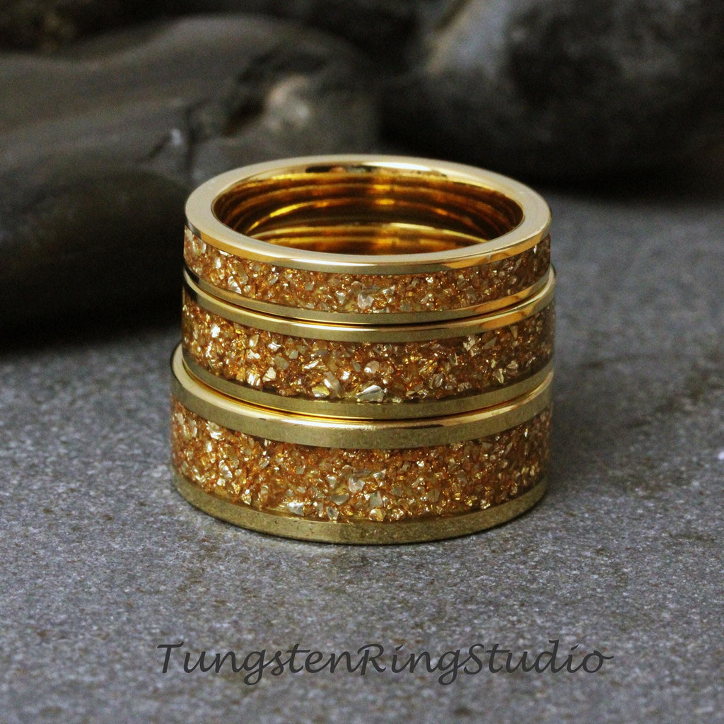 May include: Three gold tungsten carbide rings stacked on top of each other. The rings have a textured surface with gold flecks.