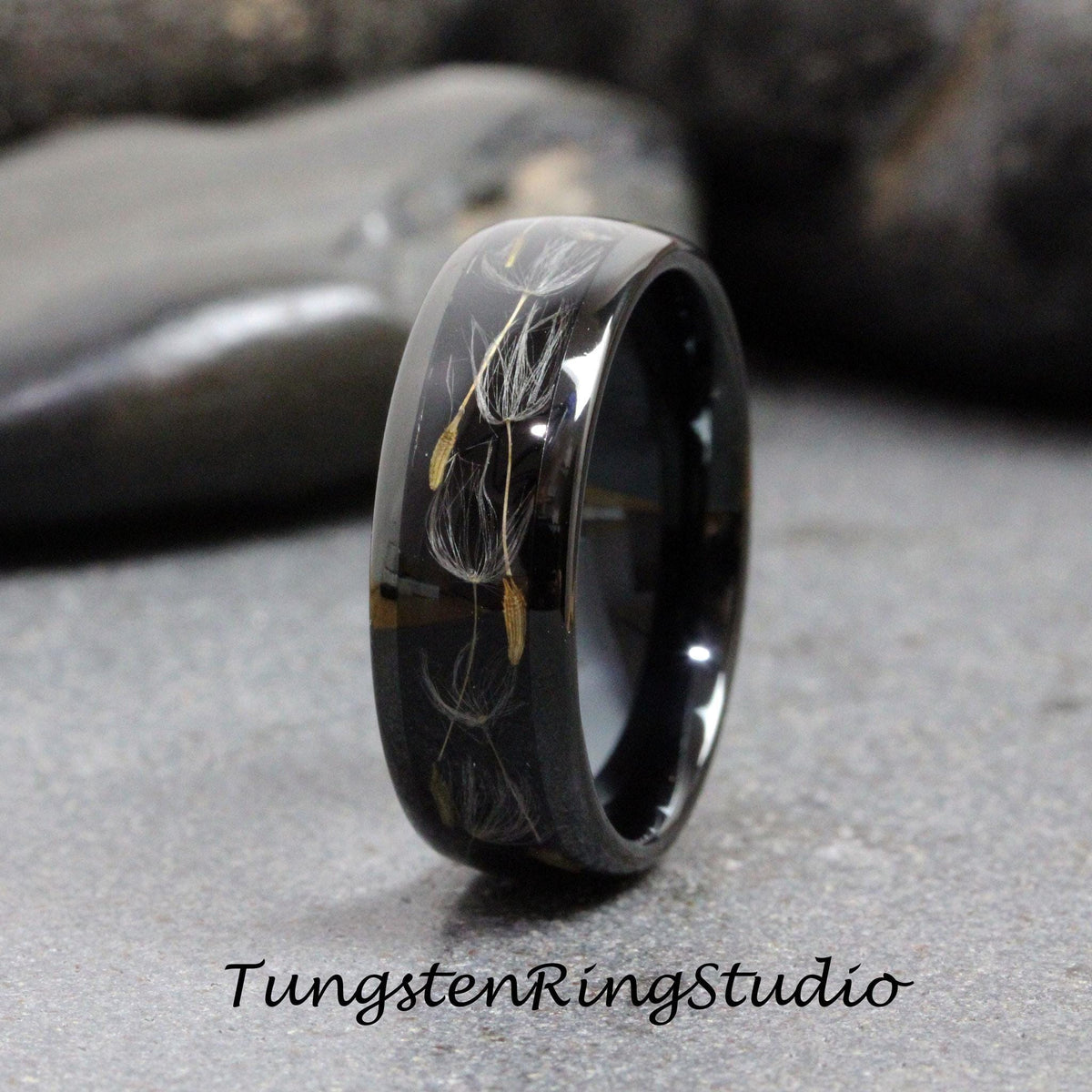 May include: A black tungsten carbide ring with a design of dandelion seeds embedded in the band.
