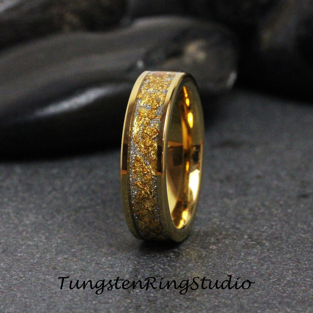 May include: A gold-colored ring with a textured, gold-colored center band and a silver-colored band. The ring is set against a dark background. The text "TungstenRingStudio" is at the bottom of the image.