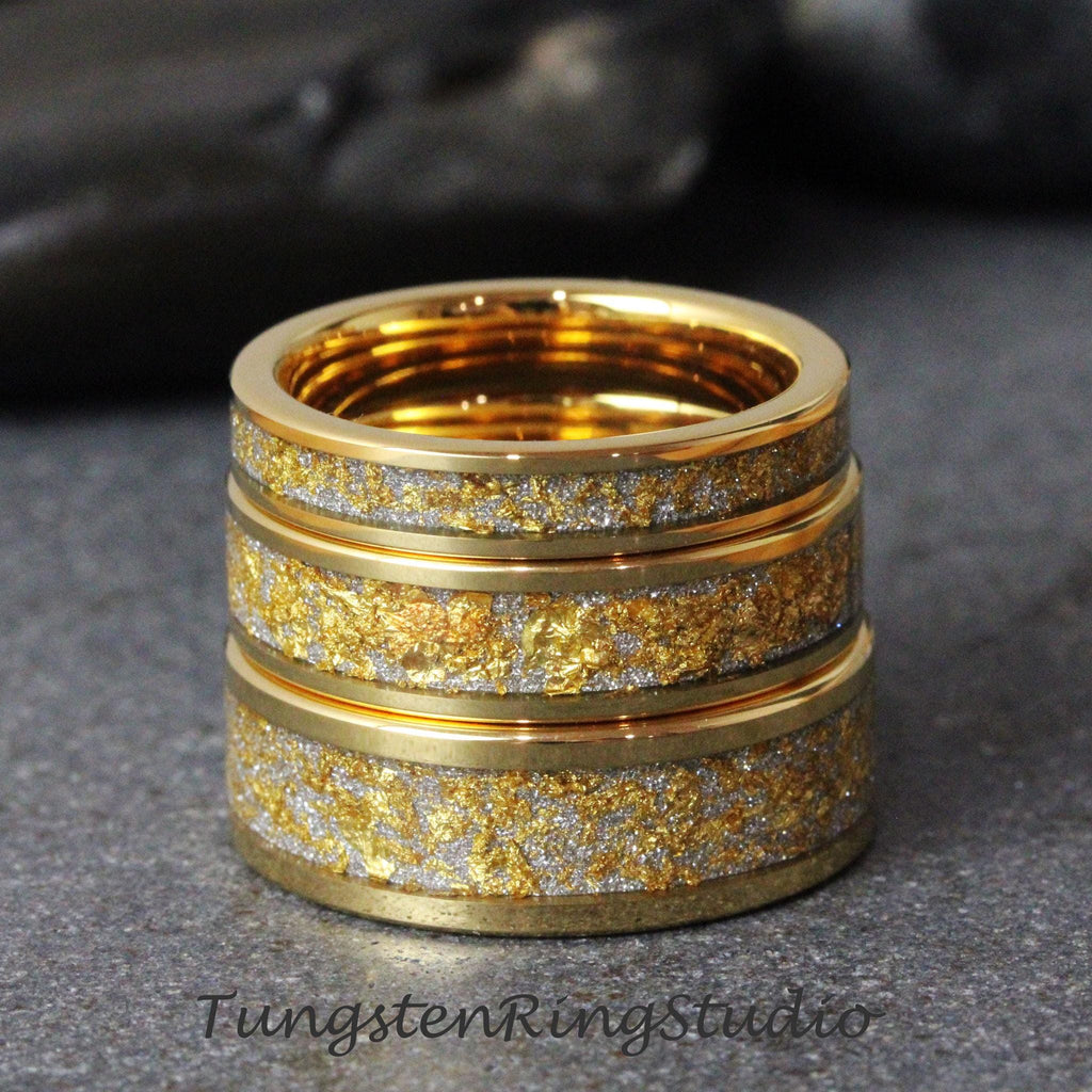May include: A stack of gold-colored rings with a textured, gold and silver band. The rings have a shiny, metallic finish and are stacked on top of each other. The rings are on a gray surface.