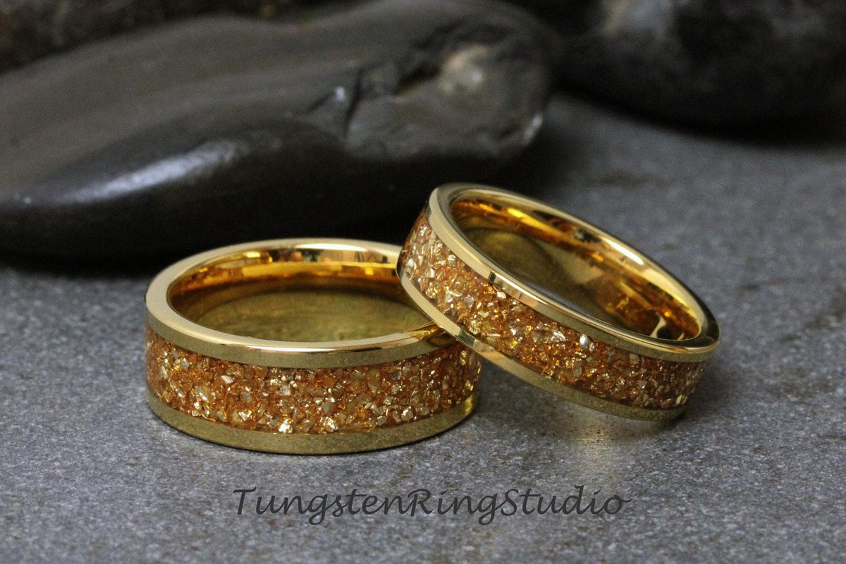 May include: Two gold tungsten carbide rings with a textured, sparkly finish. The rings are stacked on top of each other.