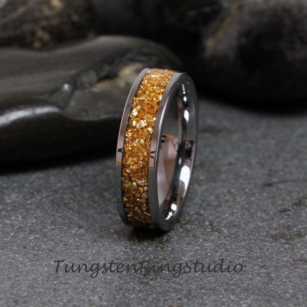 May include: A tungsten carbide ring with a band of gold glitter. The ring is a simple design with a polished finish.