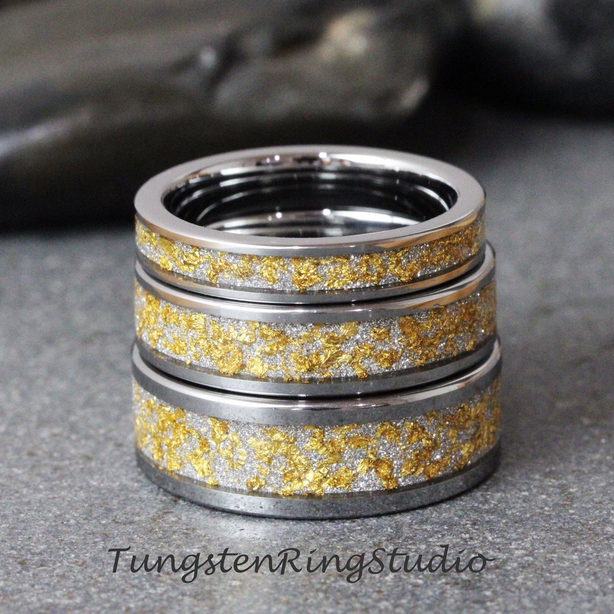 May include: Three silver tungsten rings with a gold inlay. The rings are stacked on top of each other.