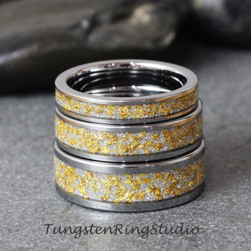 May include: Three silver tungsten rings with a gold inlay. The rings are stacked on top of each other.