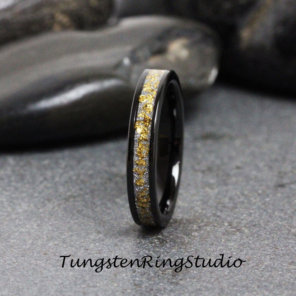 May include: A black tungsten carbide ring with a band of gold and silver glitter. The ring is a simple design with a polished finish.