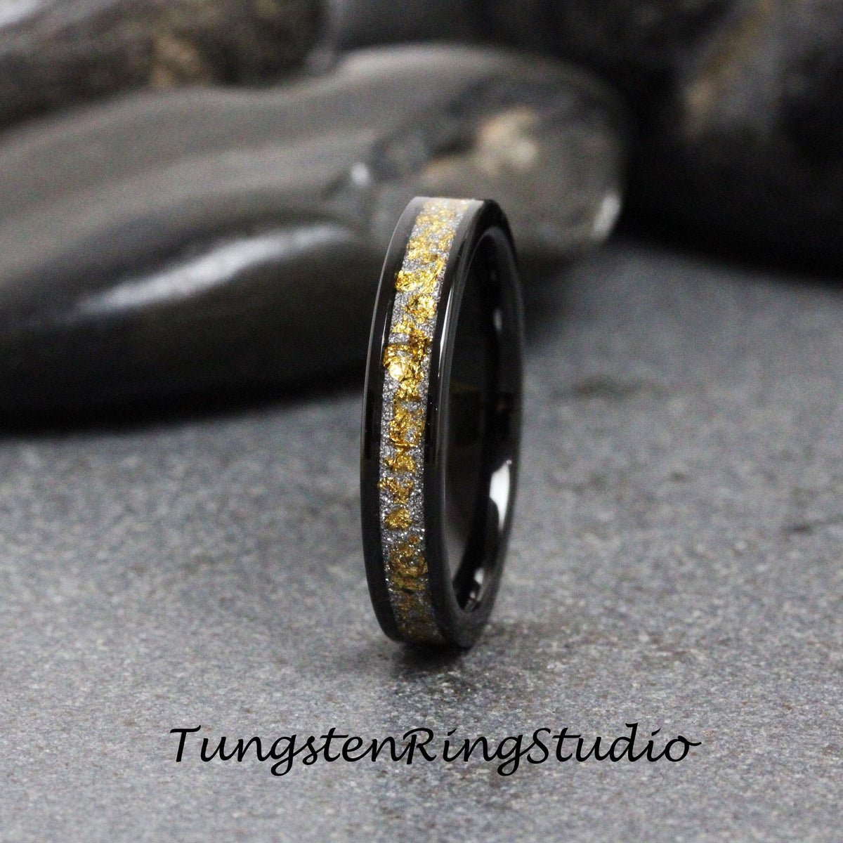 May include: A black tungsten carbide ring with a band of gold and silver glitter. The ring is a simple design with a polished finish.