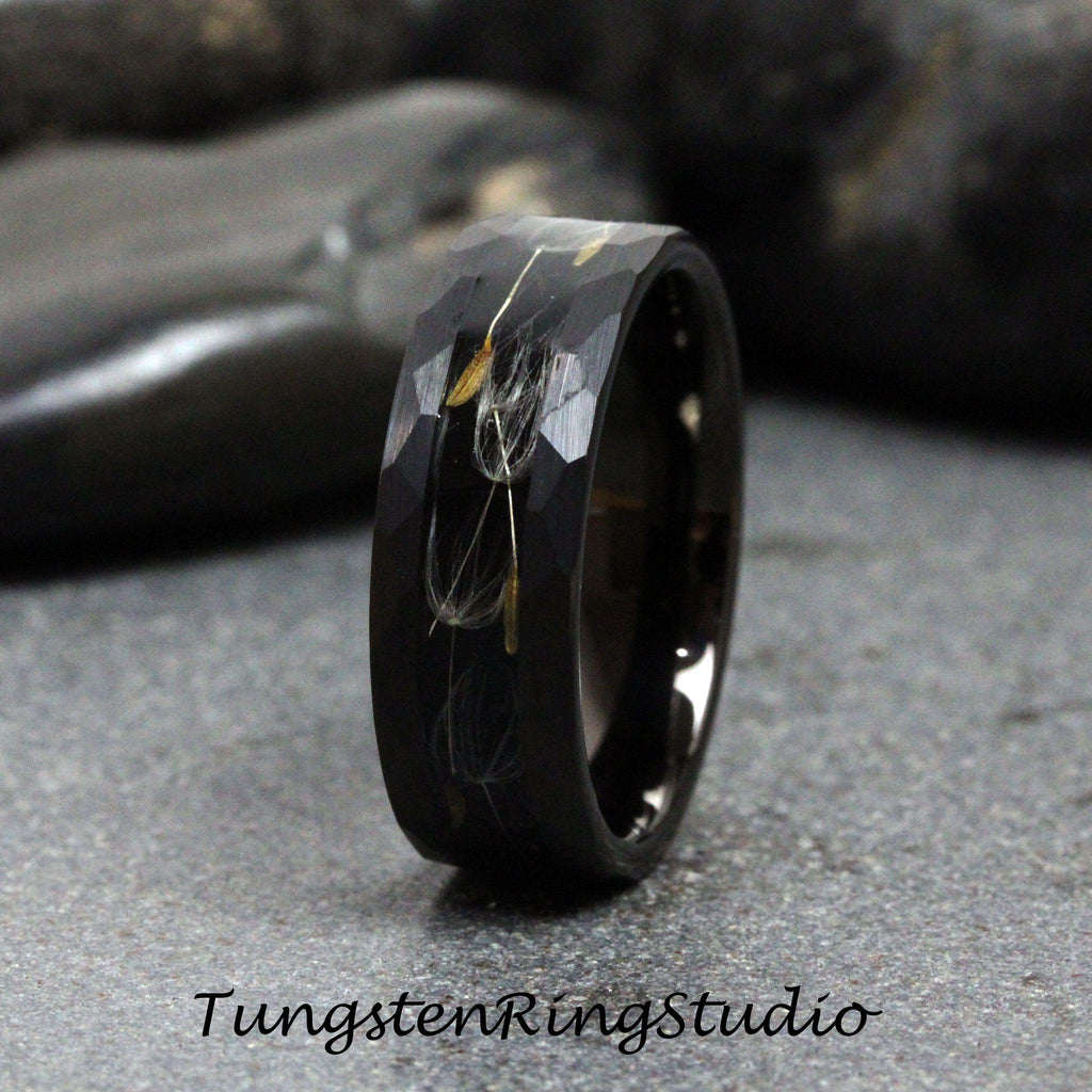 May include: A black tungsten carbide ring with a hammered finish and a band of dandelion seeds embedded in the metal.