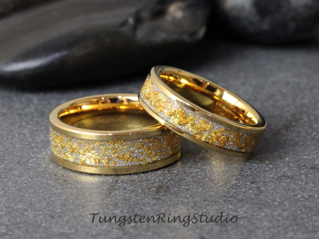 May include: Two gold tungsten carbide wedding bands with a gold and silver flecked design.