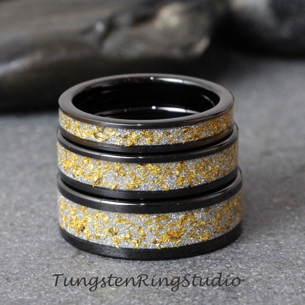 May include: Three black tungsten carbide rings with a gold and silver inlay. The rings are stacked on top of each other.