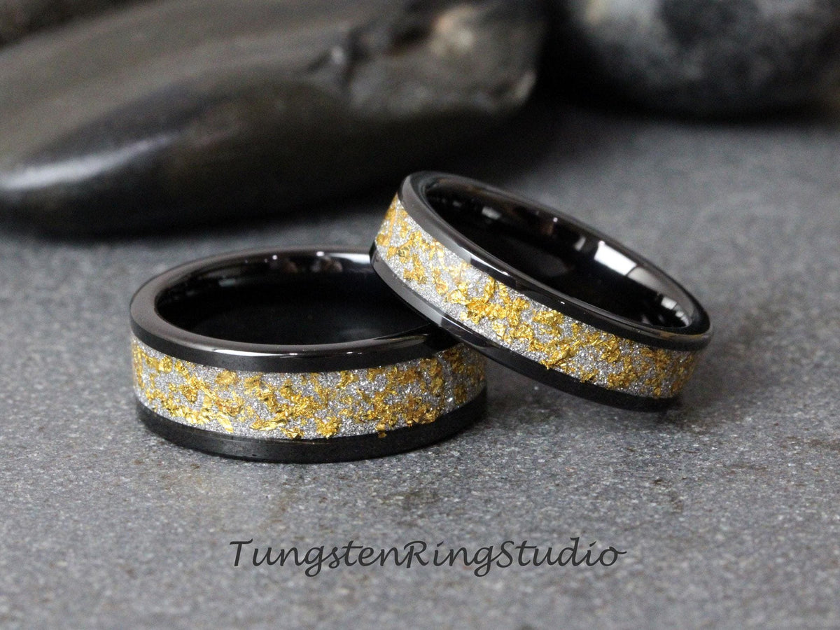 May include: Two black tungsten carbide rings with a gold and silver inlay. The rings are stacked on top of each other.