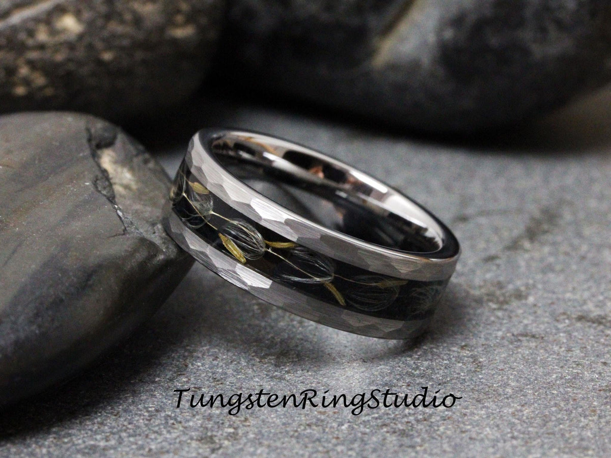 May include: A silver tungsten ring with a black inlay and a hammered finish. The inlay features a design of small, black and gold flowers.