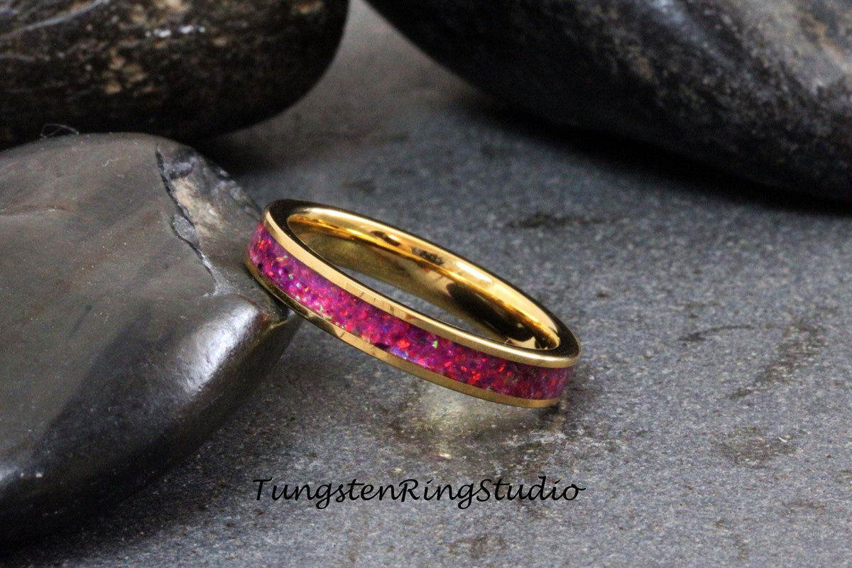 May include: A gold tungsten ring with a pink opal inlay. The ring is on a gray background.