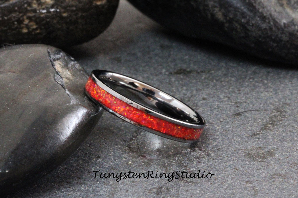 May include: A black tungsten ring with a red opal inlay. The ring is on a gray background.