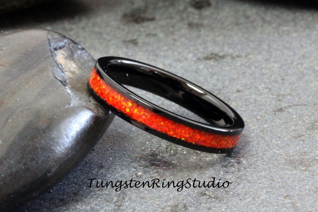 May include: Black tungsten carbide ring with a thin red opal inlay.