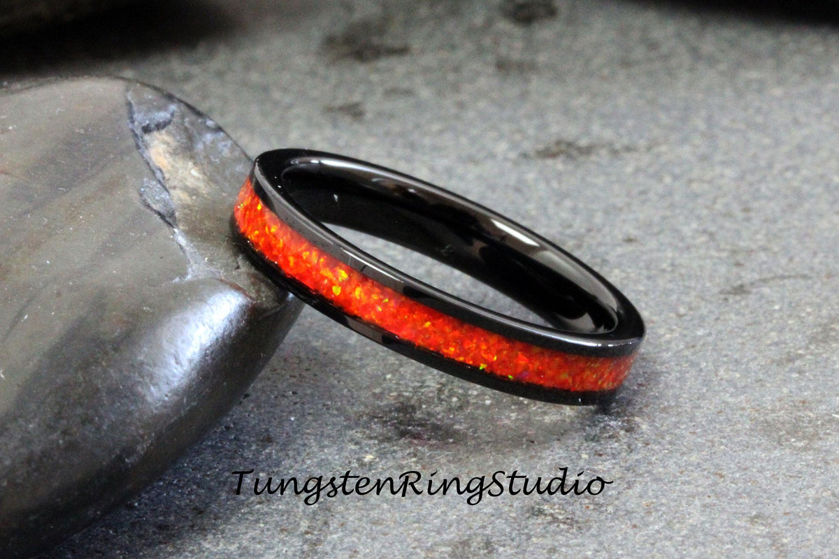 May include: Black tungsten carbide ring with a thin red opal inlay.