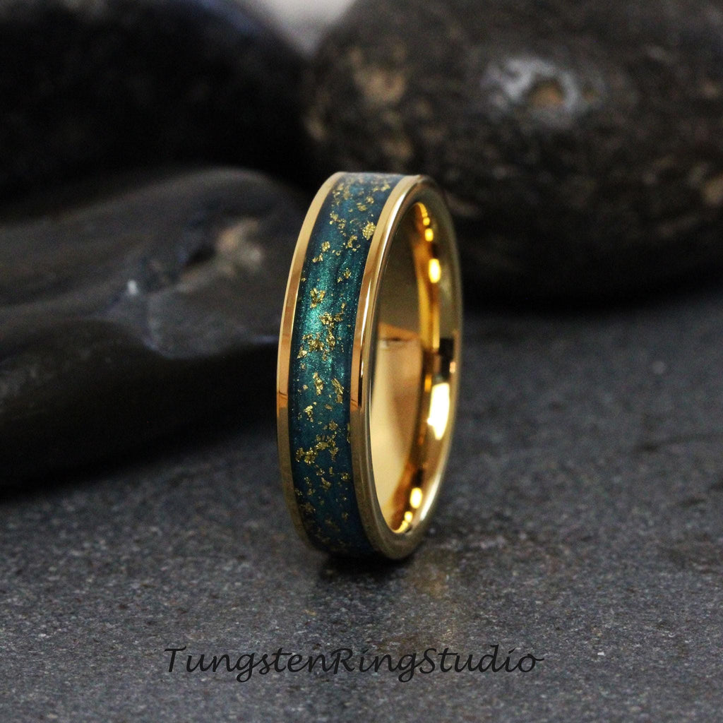 May include: A gold tungsten carbide ring with a teal blue inlay and gold flecks. The ring is a classic wedding band style.