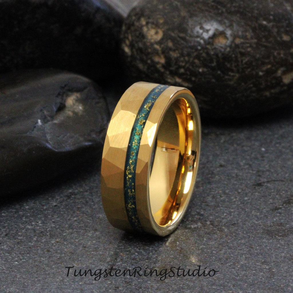 May include: A gold tungsten carbide ring with a green and gold inlay. The ring has a hammered finish.