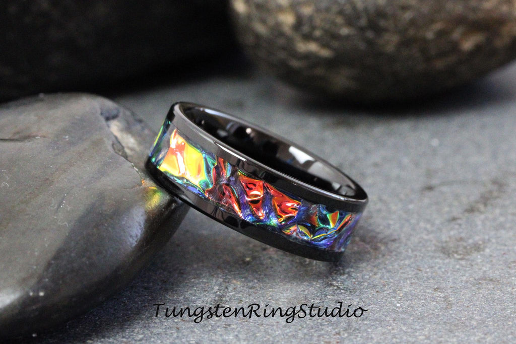 May include: Black tungsten ring with a colorful inlay design. The inlay features a swirling pattern of red, orange, yellow, blue, and green.