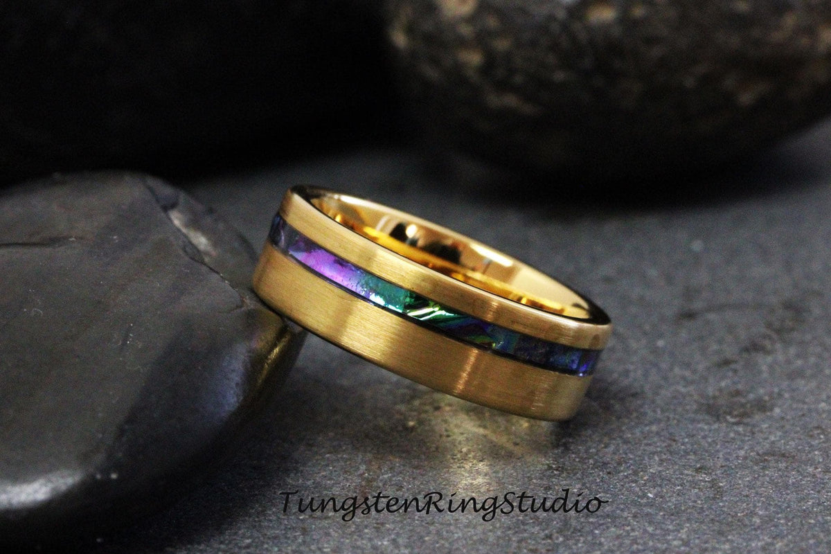May include: A gold tungsten ring with a thin inlay of iridescent abalone shell. The ring has a brushed finish.