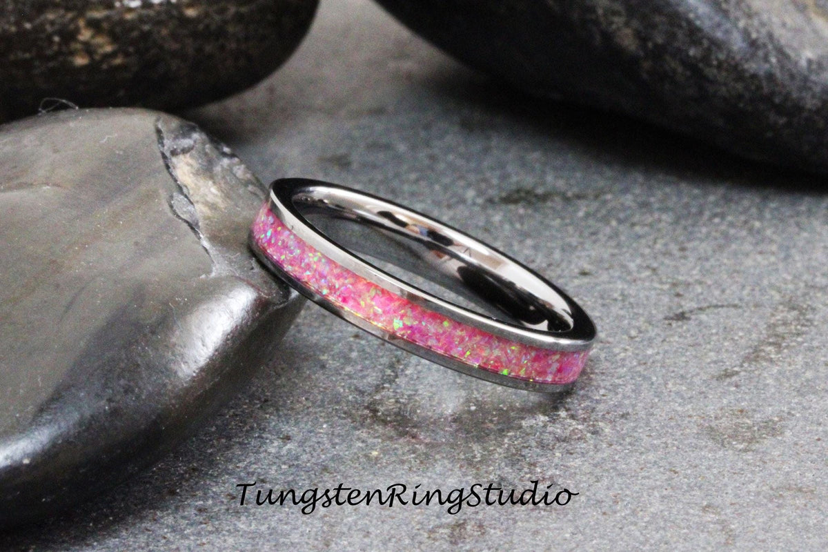 May include: A silver tungsten ring with a pink opal inlay. The ring is on a gray background.