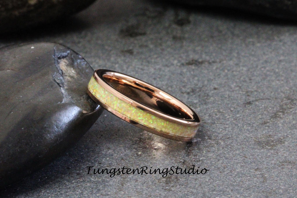 May include: A rose gold tungsten carbide ring with a thin band of white opal inlay. TungstenRingStudio is printed below the ring.