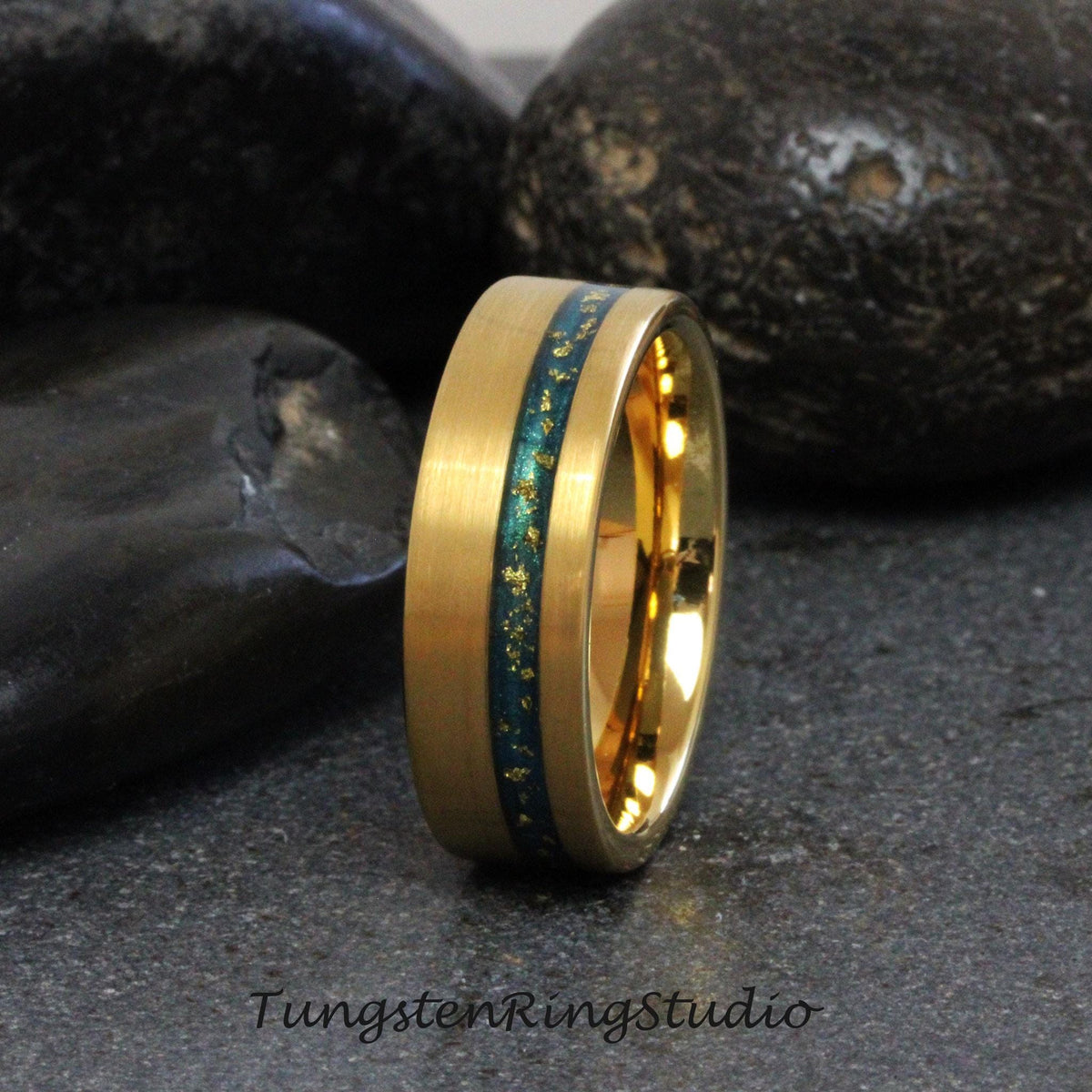 May include: A gold tungsten carbide ring with a green and gold inlay. The ring has a brushed finish and a beveled edge.