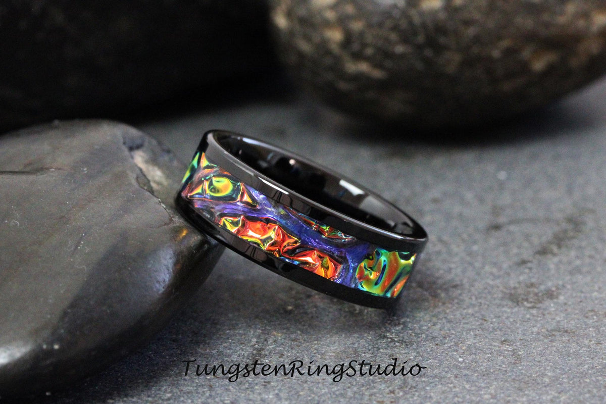 May include: A black tungsten ring with a colorful inlay design. The inlay features a swirling pattern of orange, yellow, green, blue, and purple.