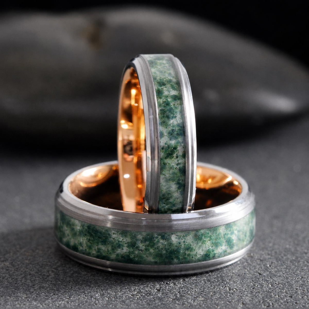 May include: Two rings featuring a brushed silver-tone outer band with a central inlay of mottled green stone. The interior of each ring is a polished rose gold-tone metal. One ring is positioned vertically, while the other lies flat horizontally.